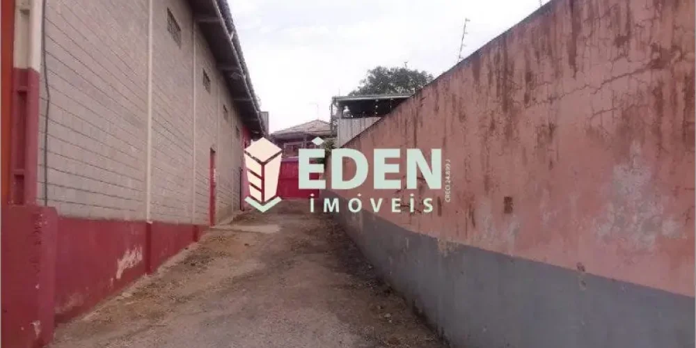 Fachada de galpão comercial com portão grande, rua pavimentada e muros altos no bairro Éden, em Sorocaba, SP.