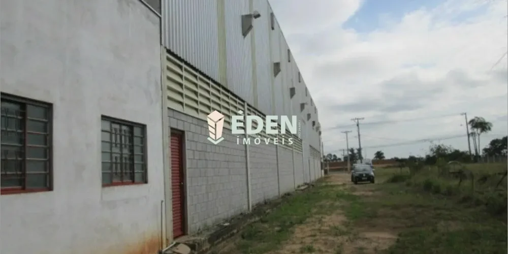 Fachada de galpão industrial com portão grande, paredes claras e amplo espaço frontal, localizado em Cajuru do Sul, Sorocaba, São Paulo.
